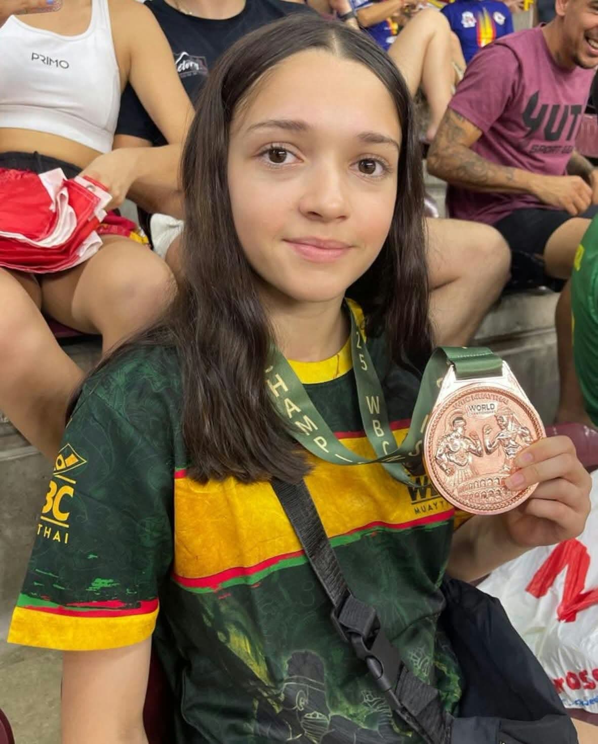 Teenage girl holding a WBC Muay Thai world championship medal